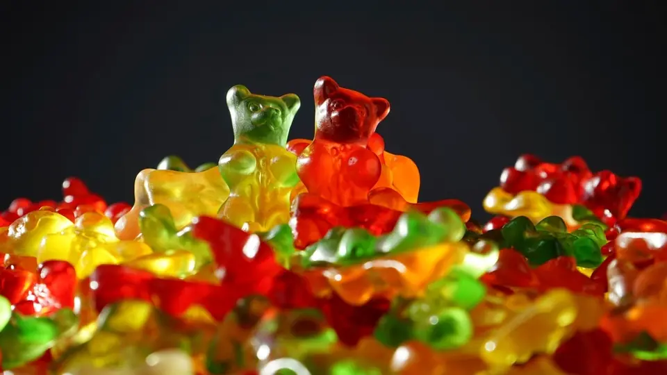 Ositos de goma rojos, amarillos y verdes sobre fondo oscuro